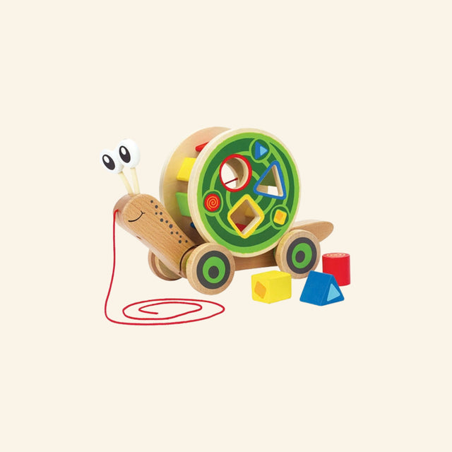 Hape Walk-A-Long Snail shown with the wooden snail body, colorful shape-sorting shell, red pull string, and three loose shape blocks in yellow, red, and blue.