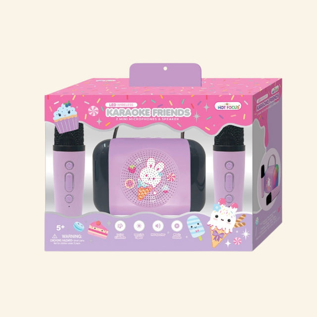 Hot Focus Wireless Karaoke Friends – Sweets retail box showing a pastel pink LED speaker with bunny ice cream artwork, two pink mini microphones, candy and sprinkle-themed packaging, and icons for lyrics eliminator, dancing lights, HiFi speaker, and magic sounds.