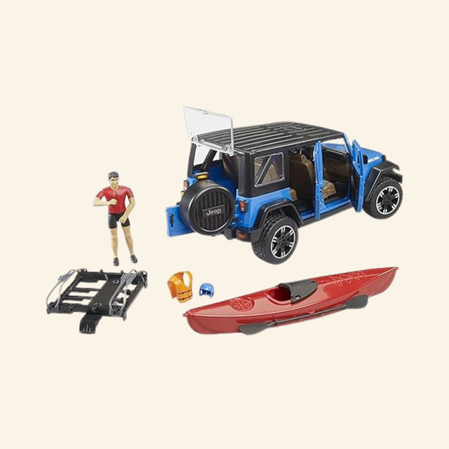 Bruder Jeep Wrangler Rubicon adventure playset with open doors and removable roof, plus red kayak, paddle, helmet, kayaker figure, and roof rack displayed separately.