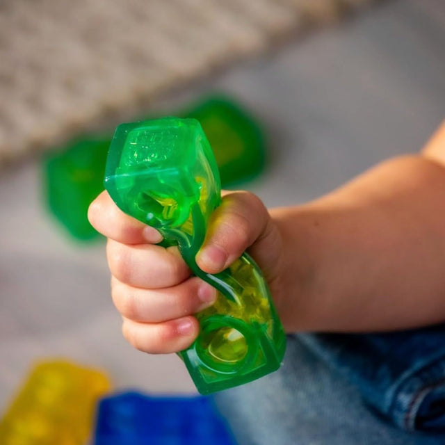 Hand holding a green plastic block with a blurred background