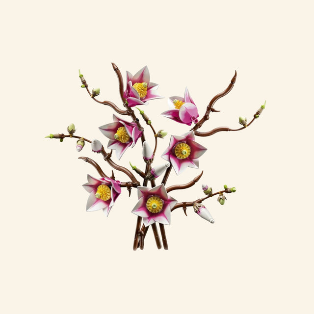 Completed LEGO Botanicals Magnolia Branches arrangement featuring five twisting brown branches with open pink-and-white magnolia flowers, green buds, and partially opened blossoms.