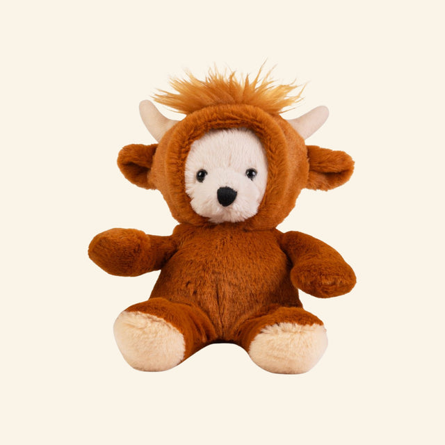 Keycraft Little Dress Up Bear – Highland Cow plush shown seated in a soft brown Highland cow costume with cream bear face, cream paws, small horns, floppy ears, and fuzzy orange hair on the removable hood.