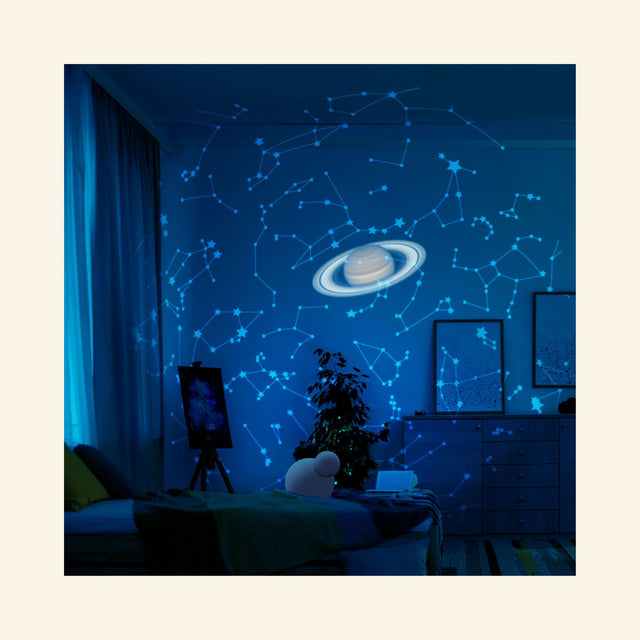 Bedroom ceiling illuminated by the Thames & Kosmos Planetarium Projector, showing blue constellation patterns and a projected image of Saturn above the room.
