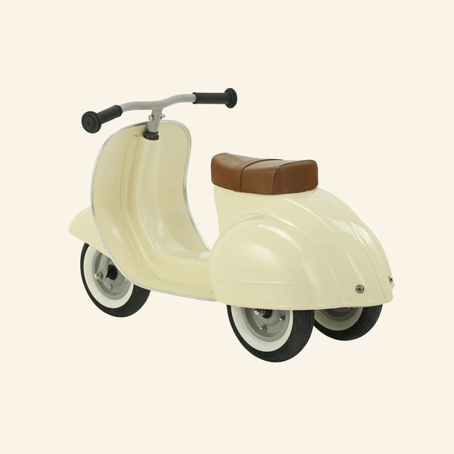 Angled front view of the AMBOSSTOYS PRIMO cream ride-on toy with a brown seat.