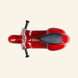Top view of the AMBOSSTOYS PRIMO ride-on toy scooter in red showing the black seat and handlebar layout.
