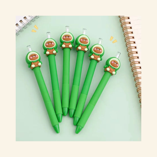 Avocado Bear Retractable Pencils arranged on a mint green desk beside a spiral notebook, showing bright green pencil barrels topped with cute bear characters wearing avocado-style hoods.