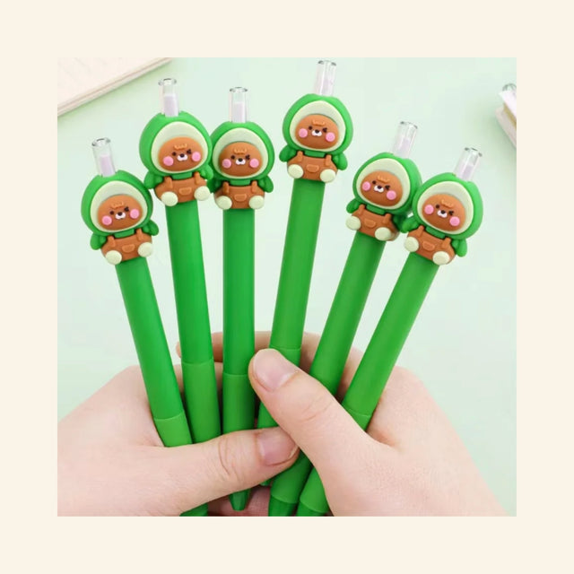 Hand holding several Avocado Bear Retractable Pencils with green barrels and adorable avocado bear toppers, showing the clear retractable pencil tips and matching character designs.