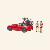 Bruder Red Roadster with Road Bike and Cyclist set showing the red roadster with bikes mounted on the rear rack and Bruder figures standing beside the car.