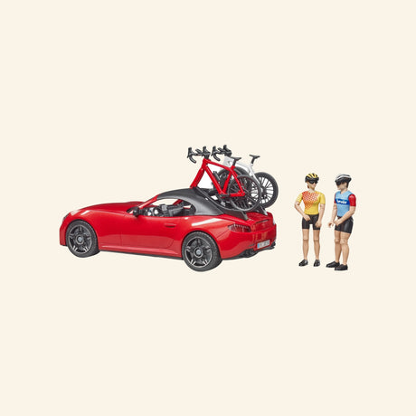 Bruder Red Roadster with Road Bike and Cyclist set showing the red roadster with bikes mounted on the rear rack and Bruder figures standing beside the car.