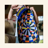 Child holding the Doinkit Darts Rollup Magnetic Dartboard during family game play.