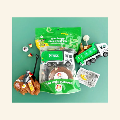Earth Grown KidDoughs Garbage KidDough Play Kit shown with green retail bag packaging, brown root beer-scented dough, green garbage truck, raccoon figure, shovel, pretend trash pieces, banana peel, bottle, apple cores, and activity sheet arranged on a teal background.