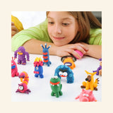 Child playing with Fat Brain Toys Hey Clay – Monsters, sculpting colorful monster figures while looking at the completed clay characters on the table.