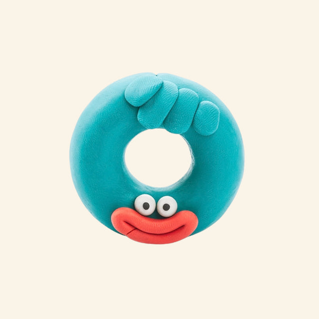 Fat Brain Toys Hey Clay – Monsters turquoise donut-shaped monster character shown with a round body, center opening, big eyes, red mouth, and small textured details.