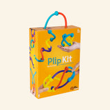 at Brain Toys Plip Kit retail box with orange packaging, colorful silicone Plip pieces attached to the front, a carry handle, and a child’s hand shown connecting pieces.