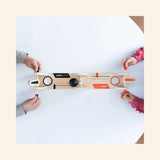 Overhead play view of Fat Brain Toys VolleyShot Game with two players’ hands on the paddle controls as the attached ball moves across the tabletop game.
