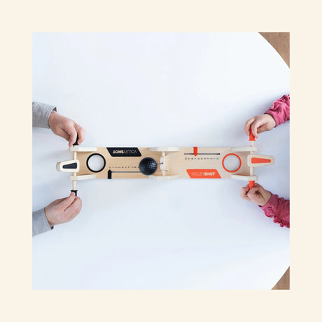Overhead play view of Fat Brain Toys VolleyShot Game with two players’ hands on the paddle controls as the attached ball moves across the tabletop game.