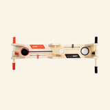 Fat Brain Toys VolleyShot Game shown from above, featuring two opposing paddle controls, the attached ball, wooden rails, and the narrow tabletop play surface.