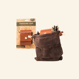 Find New Roots Foraging Bag shown open beside its product card, with a brown waxed-canvas pouch, leather-style front flap, drawstring closure, and a pinecone tucked near the top.