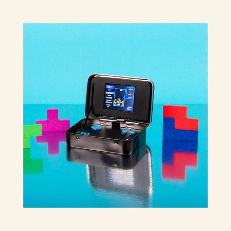 Fizz Creations Tetris Arcade in a Tin shown open on a bright blue background, with the handheld game screen and controls visible beside colorful Tetris block shapes.