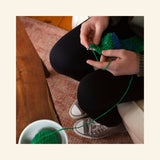 Person learning to crochet with the Friendly Loom Discover Crochet Scarf Kit using green practice yarn.
