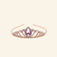 Great Pretenders Boutique Regal Tiara shown in rose gold with sparkling rhinestones, curved crown detailing, and a large pink teardrop gemstone centerpiece.