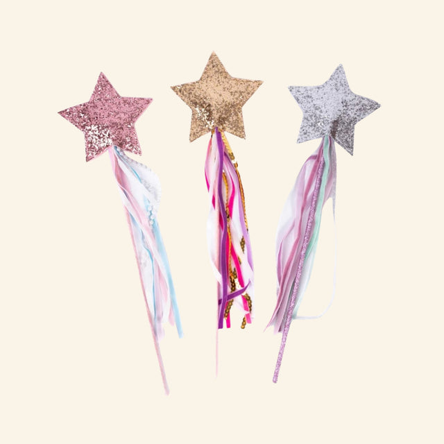 Great Pretenders Deluxe Twinkle Star Wand assortment showing pink, gold, and silver glitter star wands with flowing ribbons, sequins, and pearl-style embellishments.