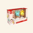 Hape Cheery Critter Rattle Trio shown in retail packaging with mouse, rabbit, and chick baby rattles, suction cup bases, Hape branding, and baby play photo on the box.