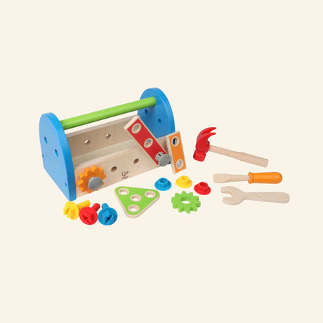 Hape Fix-It Tool Box pieces displayed outside the toolbox, showing the wooden toolbox, hammer, screwdriver, wrench, ruler, gears, links, bolts, and nuts for pretend building play.