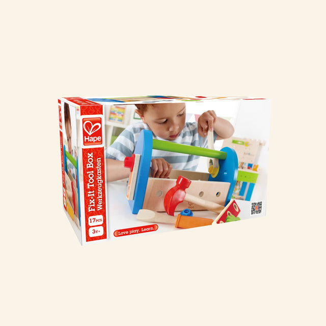 Hape Fix-It Tool Box shown in retail packaging with a child using the wooden toolbox, colorful tools, construction pieces, and age 3+ guidance on the box.