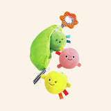 Hape Pea Pod Pals shown out of the box with a green fabric pea pod holding three smiling plush peas in green, pink, and yellow, plus an attached orange rattling flower and striped loop.
