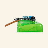 Hape Railway Bucket Builder Set green storage bucket used as a hill, with a wooden track ramp leading to the top and a train car traveling across the elevated section.