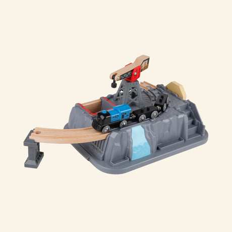 Hape Railway Bucket Builder Set gray bucket lid used as a rocky mountain scene, with wooden tracks running through the elevated section and train cars moving across the top.