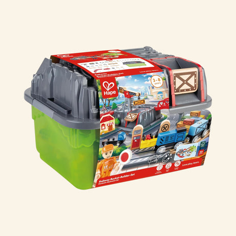 Hape Railway Bucket Builder Set shown packed in its green storage bucket with gray lid, colorful product label, railway pieces visible on the outside, and carry-ready bucket design.