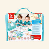 Back of the Hape Super Smile Dental Clinic Set packaging showing children playing dentist, the turquoise carrying case, mouth model, tools, activity cards, and educational play feature details.