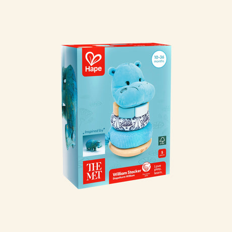 Hape The Met Collection William Stacker shown in retail packaging with a blue hippo stacking toy, The Met logo, Hape branding, age 10–36 months guidance, and artwork inspired by William the Egyptian faience hippo.