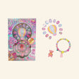 Hot Focus Dazzle Nails – Rainbow set shown with retail packaging, colorful glitter press-on nails, hot air balloon display piece, pastel bracelet with bear charm, small ring, and pink rainbow-themed artwork.