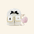 Hot Focus Stylish Beauty Mini Backpack shown from the front with white textured fabric, black bow and pearl-style accent, gold chain-trimmed front pockets, small beauty charm, and pink fuzzy heart keychain with pearl details.
