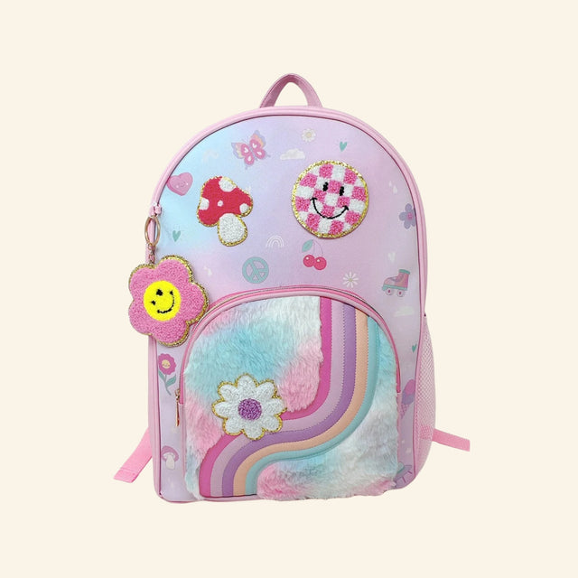 Hot Focus Trendy Backpack – Good Day shown from the front with pastel pink trim, playful printed icons, mushroom and smiley face patches, fuzzy rainbow front pocket, side mesh pocket, and pink smiley flower keychain attached to the zipper.