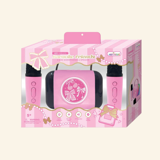 Hot Focus Wireless Karaoke Friends – Bowtiful retail box showing a pink LED speaker with bow and cherry artwork, two pink mini microphones, bow-themed packaging, and icons for lyrics eliminator, dancing lights, HiFi speaker, and magic sounds.