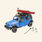 Blue Bruder Jeep Wrangler Rubicon with roof-mounted red kayak, kayaker figure, paddle, helmet, and kayaking accessories displayed beside the vehicle.