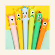 Little Monster Gel Pens shown in assorted pastel and bright colors with playful one-eyed monster toppers in pink, yellow, blue, green, and orange.