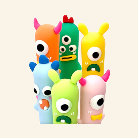 Little Monster Gel Pen character toppers shown grouped together in assorted colors, featuring playful monster faces with horns, big eyes, and silly expressions.