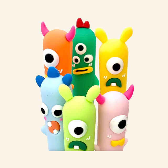 Little Monster Gel Pen character toppers shown grouped together in assorted colors, featuring playful monster faces with horns, big eyes, and silly expressions.