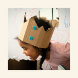 Child wearing a homemade cardboard crown fastened with blue Makedo connectors, showing how the Makedo Explore Tool Set can be used for imaginative dress-up builds.