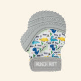 Malarkey Kids Munch Mitt shown in gray with a dinosaur print fabric mitten, textured gray silicone teething top, and adjustable wrist strap.