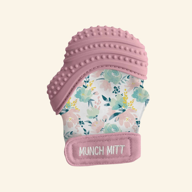 Malarkey Kids Munch Mitt shown in pink with a colorful animal print fabric mitten, textured mauve silicone teething top, and soft adjustable wrist strap.