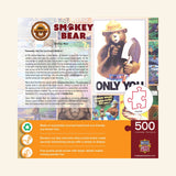 Back of MasterPieces Smokey Bear 500-piece jigsaw puzzle box showing Smokey Bear artwork, wildfrie prevention story, product features, eco-friendly materials, and actual puzzle piece size.