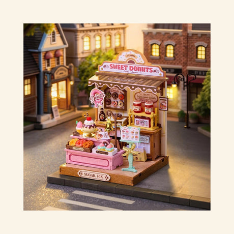 Rolife Sweetie’s Donut Shop completed miniature displayed in a street scene, showing the pastel donut shop storefront with warm lighting and tiny bakery details.