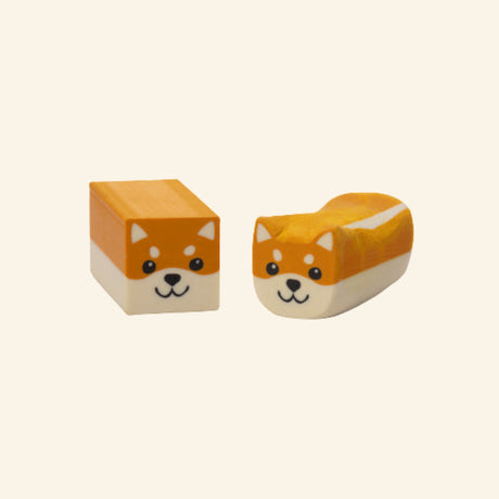 Ruff Draft Dog Eraser shown unboxed in two forms, with one cube-shaped orange dog eraser and one rounded dog-shaped eraser with a white underside and cute illustrated face.
