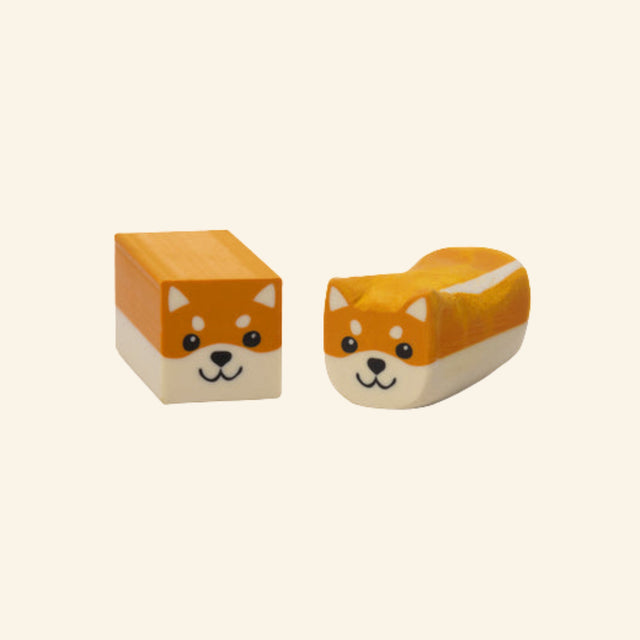 Ruff Draft Dog Eraser shown unboxed in two forms, with one cube-shaped orange dog eraser and one rounded dog-shaped eraser with a white underside and cute illustrated face.